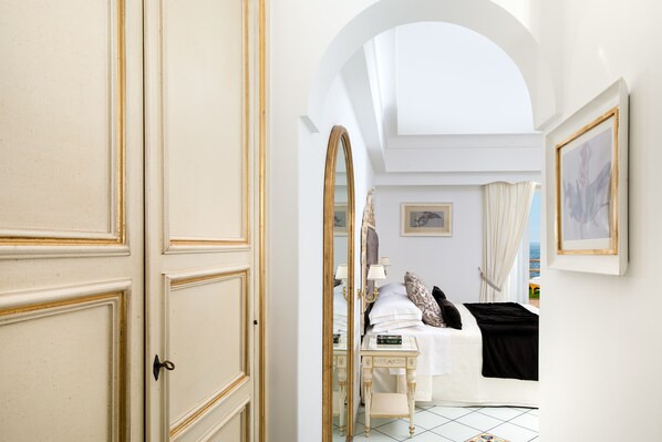 A hotel room with a large arched doorway, a bed with white linens, a bedside table with a lamp, and a view of the sea through the window. - Hotel Onda Verde (Praiano)