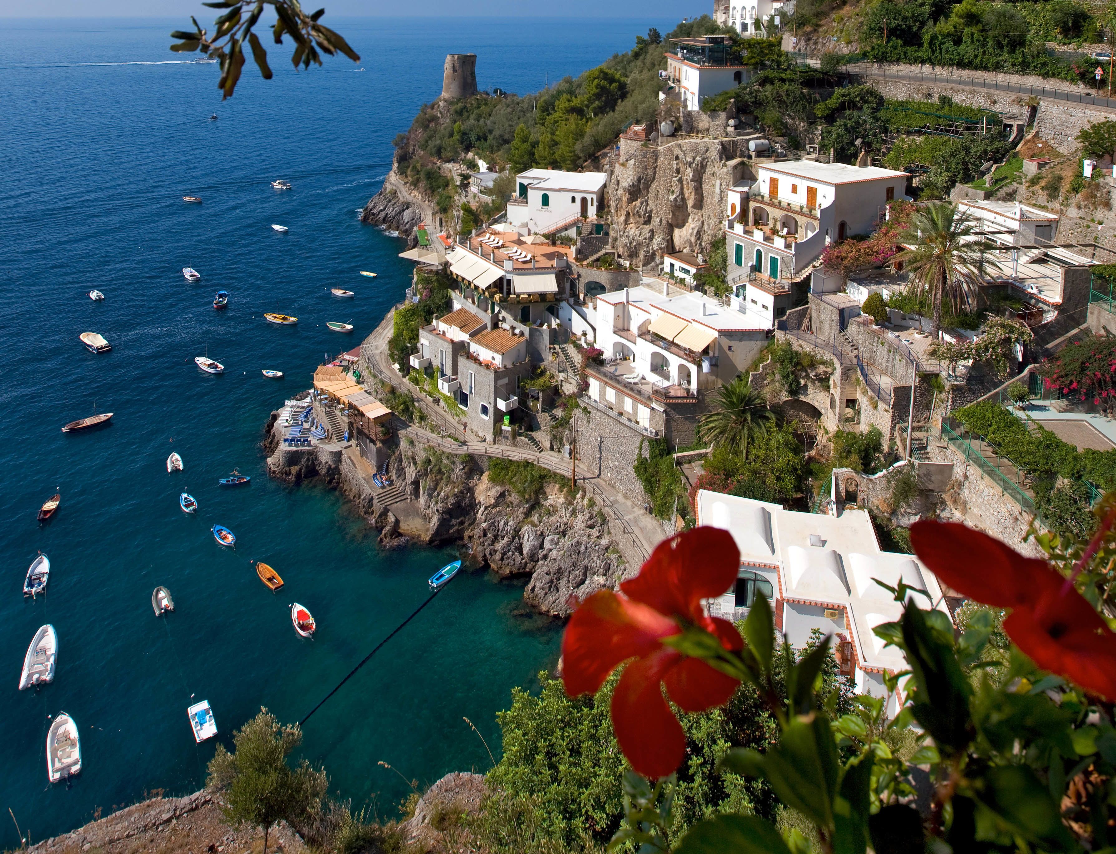 A coastal village with traditional architecture, boats on the water, and a prominent tower.