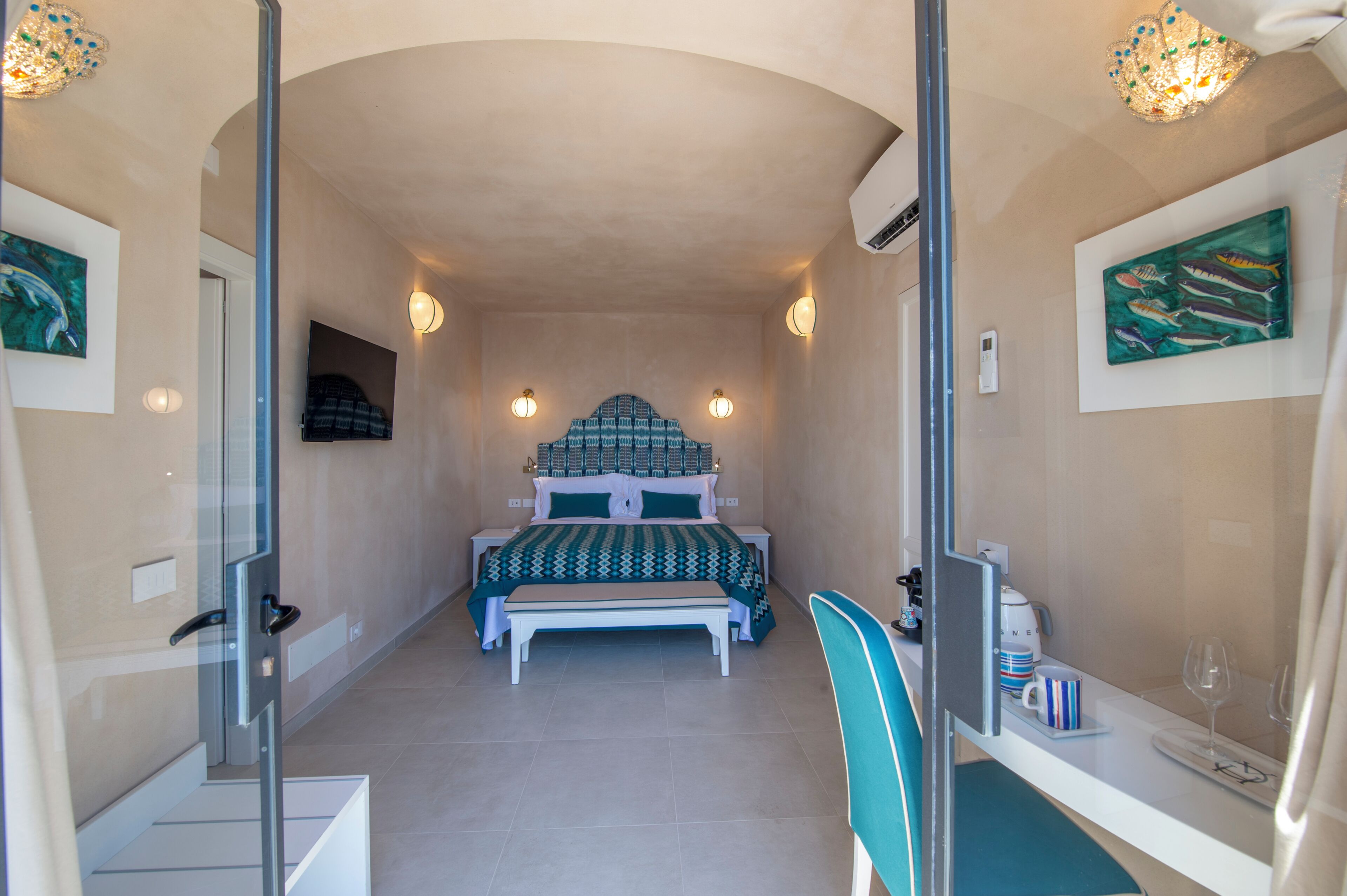 A bedroom with a bed, bedside tables, a chair, a desk, and artwork on the walls.