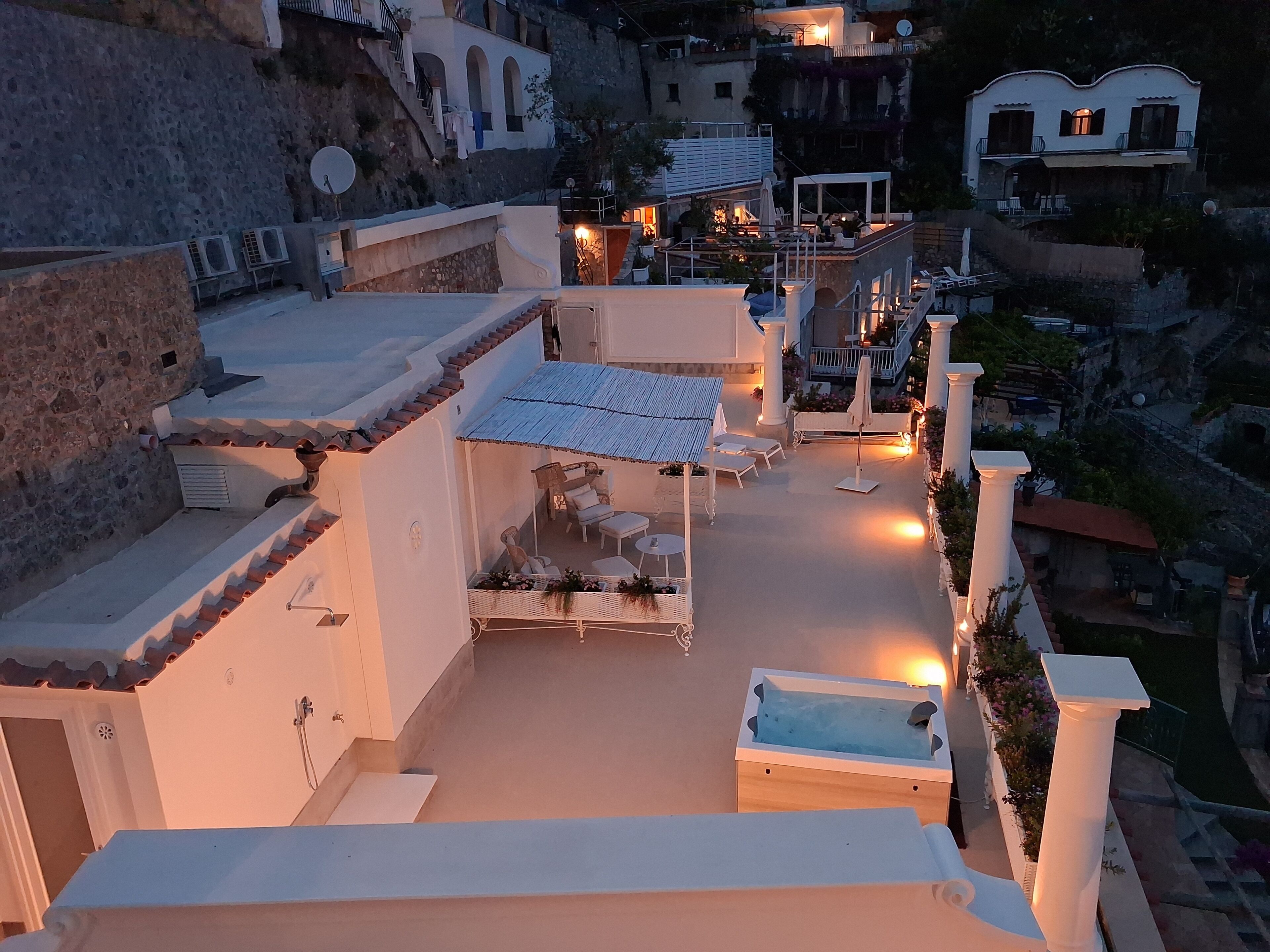 A rooftop terrace with outdoor seating, a pool, and a view of the surrounding buildings.