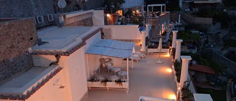 A rooftop terrace with outdoor seating, a pool, and a view of the surrounding buildings.