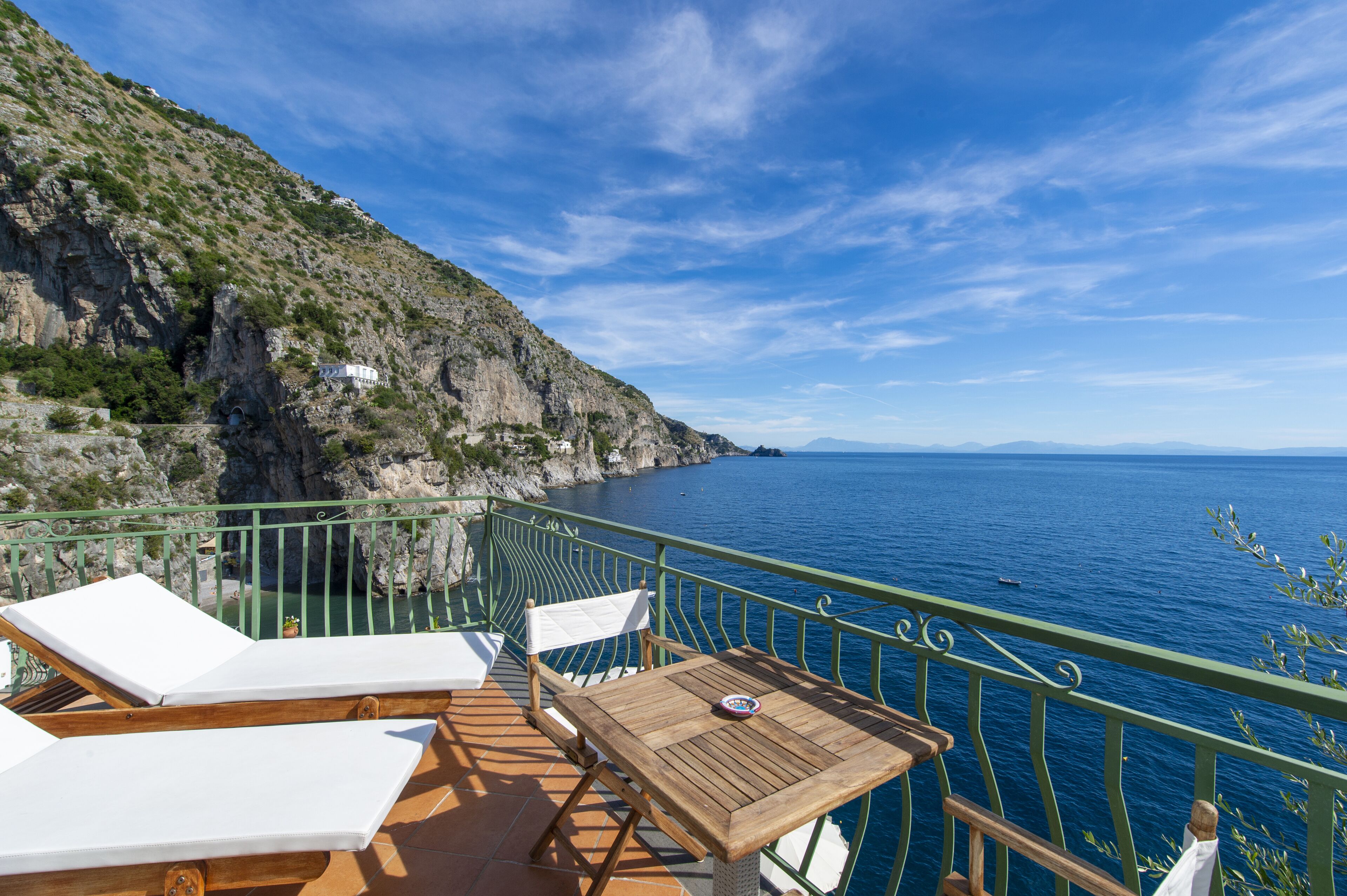 Un balcon doté de mobilier en bois et offrant une vue sur la mer.