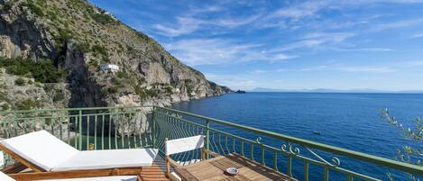 Un balcon doté de mobilier en bois et offrant une vue sur la mer.
