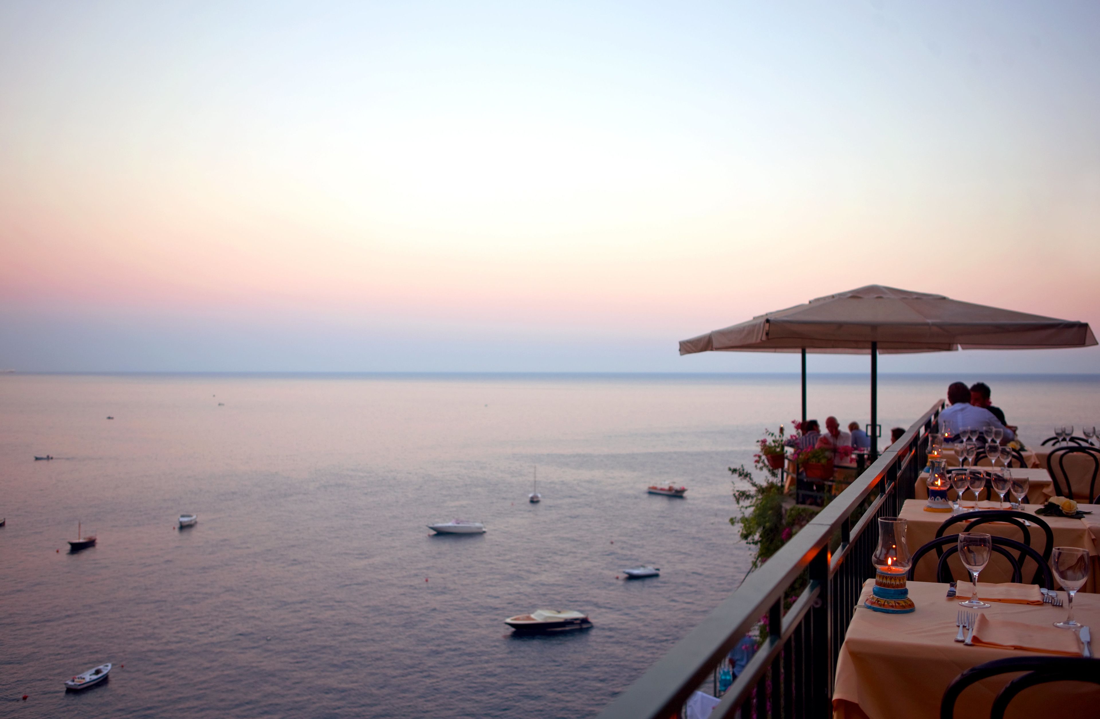 Un ristorante sul mare con tavoli e sedie, vista sul mare e barche.