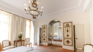 A luxurious bedroom with a large bed, a chandelier, and ornate wall decorations. - Opera Hotel (Munich)
