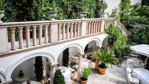 A courtyard with a stone balustrade, white columns, and potted plants. - Opera Hotel (Munich)