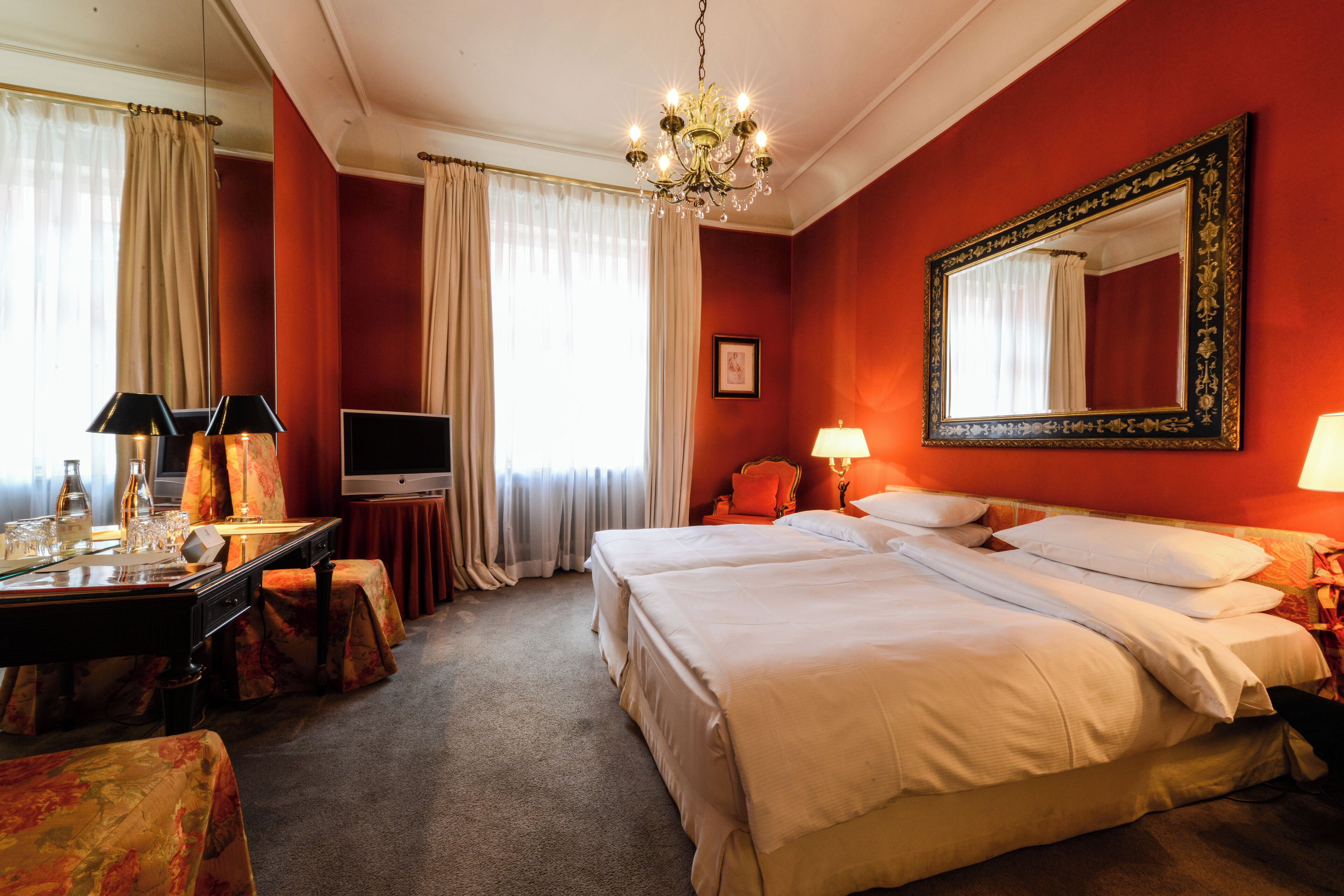 Ein Hotelzimmer mit einem großen Bett, einem Schreibtisch mit Fernseher und einer Kandelaber.