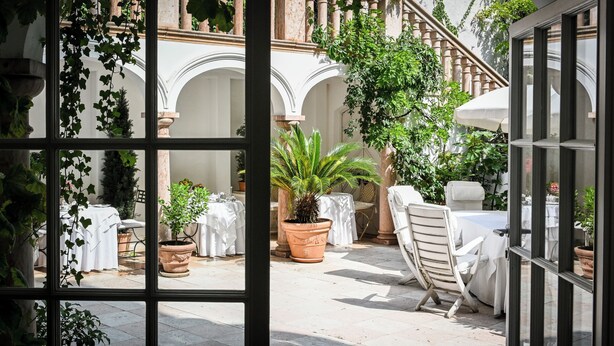 A courtyard with a table set for dining, surrounded by potted plants and a staircase. - Opera Hotel (Munich)