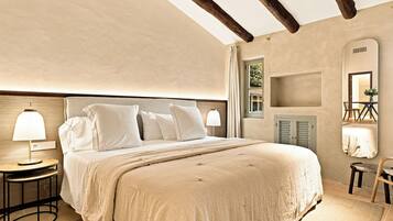 A bedroom with a large bed, two bedside tables with lamps, a wooden headboard, a mirror, and a small table with a chair.