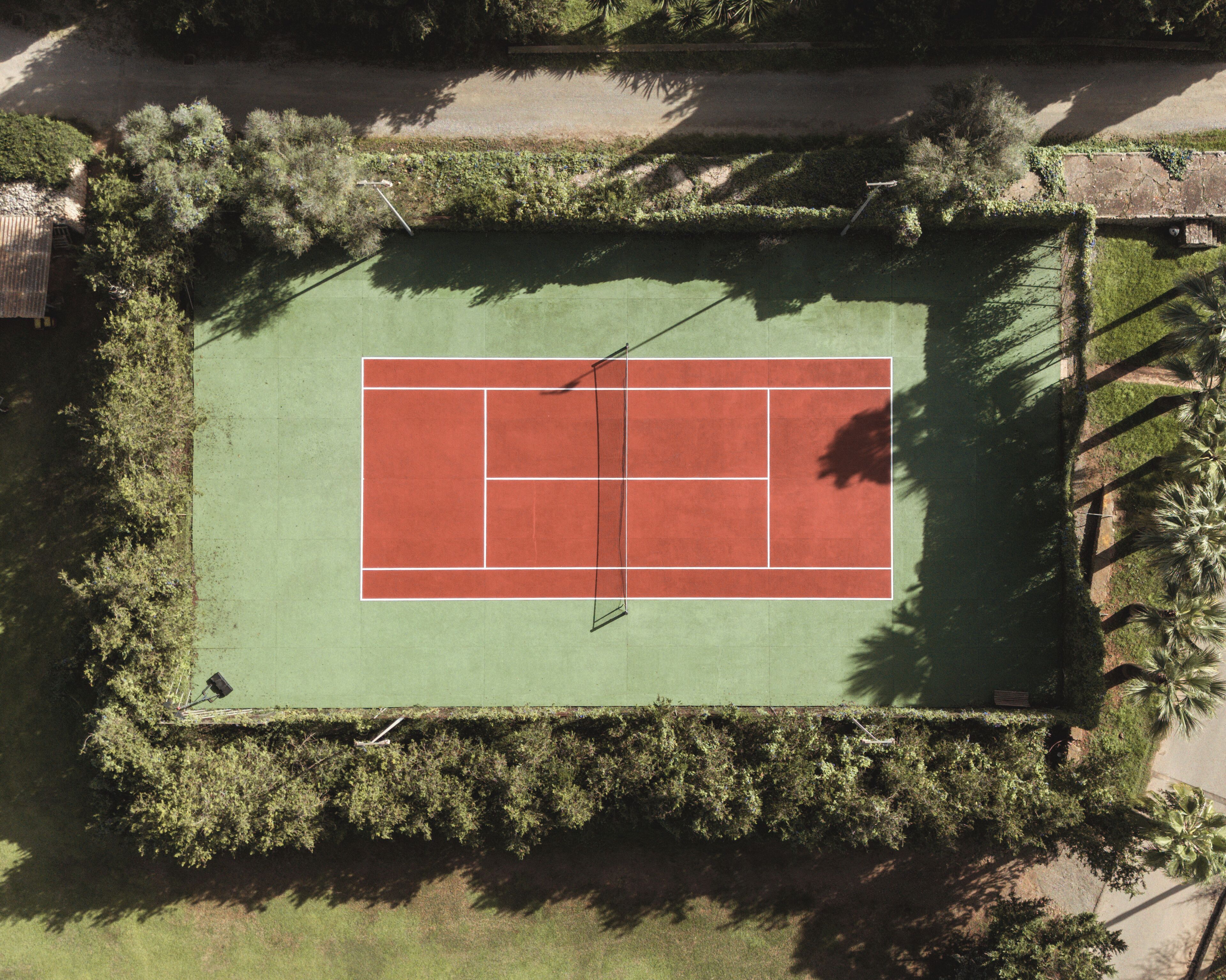 Une vue aérienne d’un court de tennis entouré d’une végétation luxuriante.