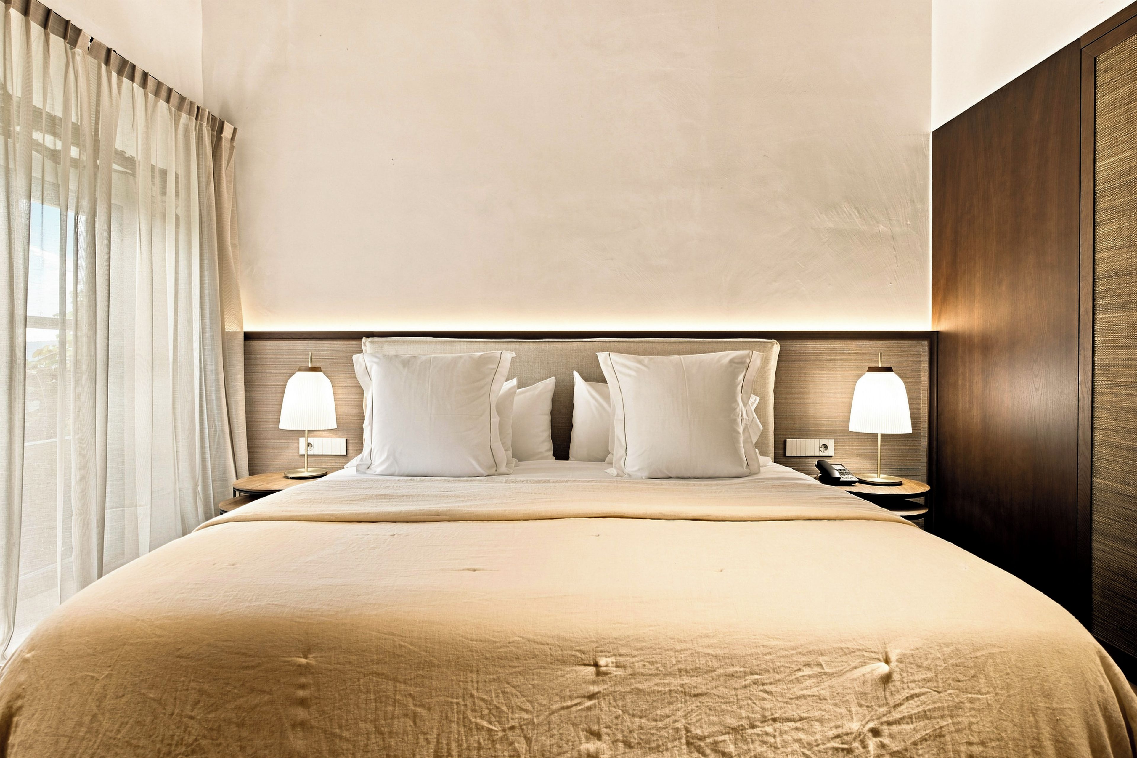 Una habitación de hotel con una cama grande, dos lámparas de noche y un cabecero de madera.
