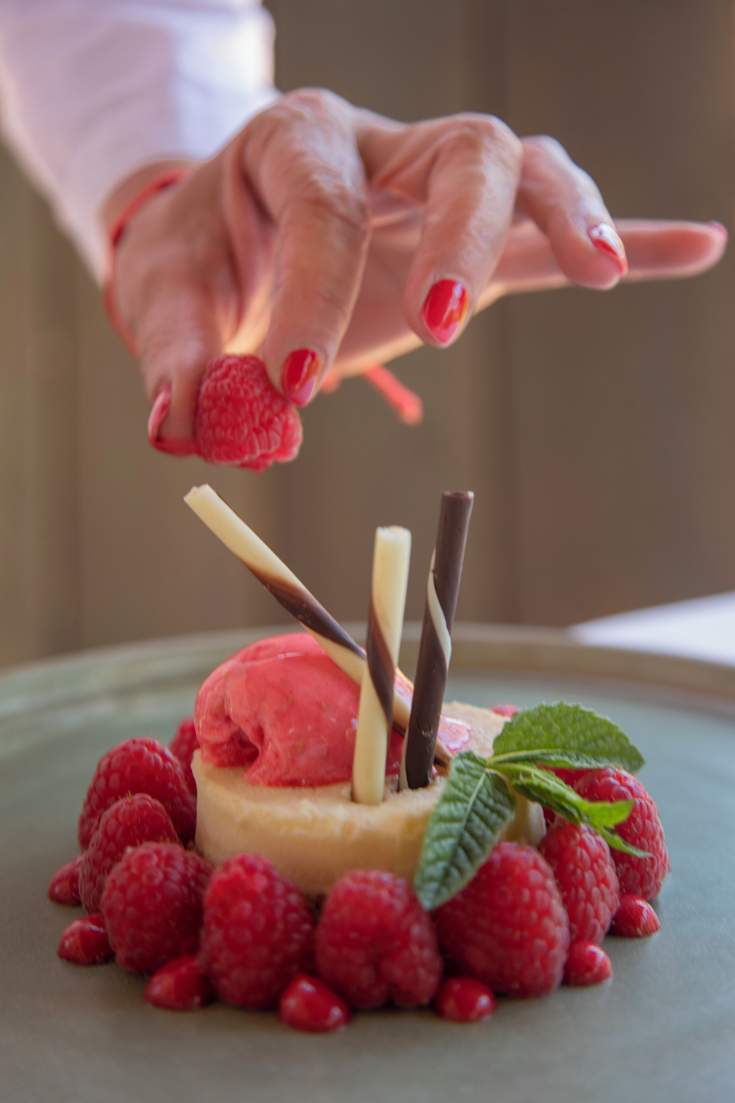 Un dessert composé de crème glacée, de bâtonnets de chocolat et de framboises, le tout présenté sur une assiette.