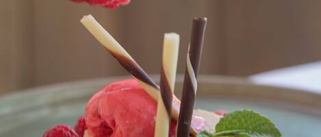 Un dessert composé de crème glacée, de bâtonnets de chocolat et de framboises, le tout présenté sur une assiette.