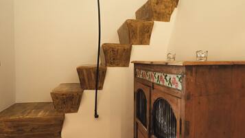 A wooden staircase with a handrail, a wooden cabinet with floral patterns, and a small table.