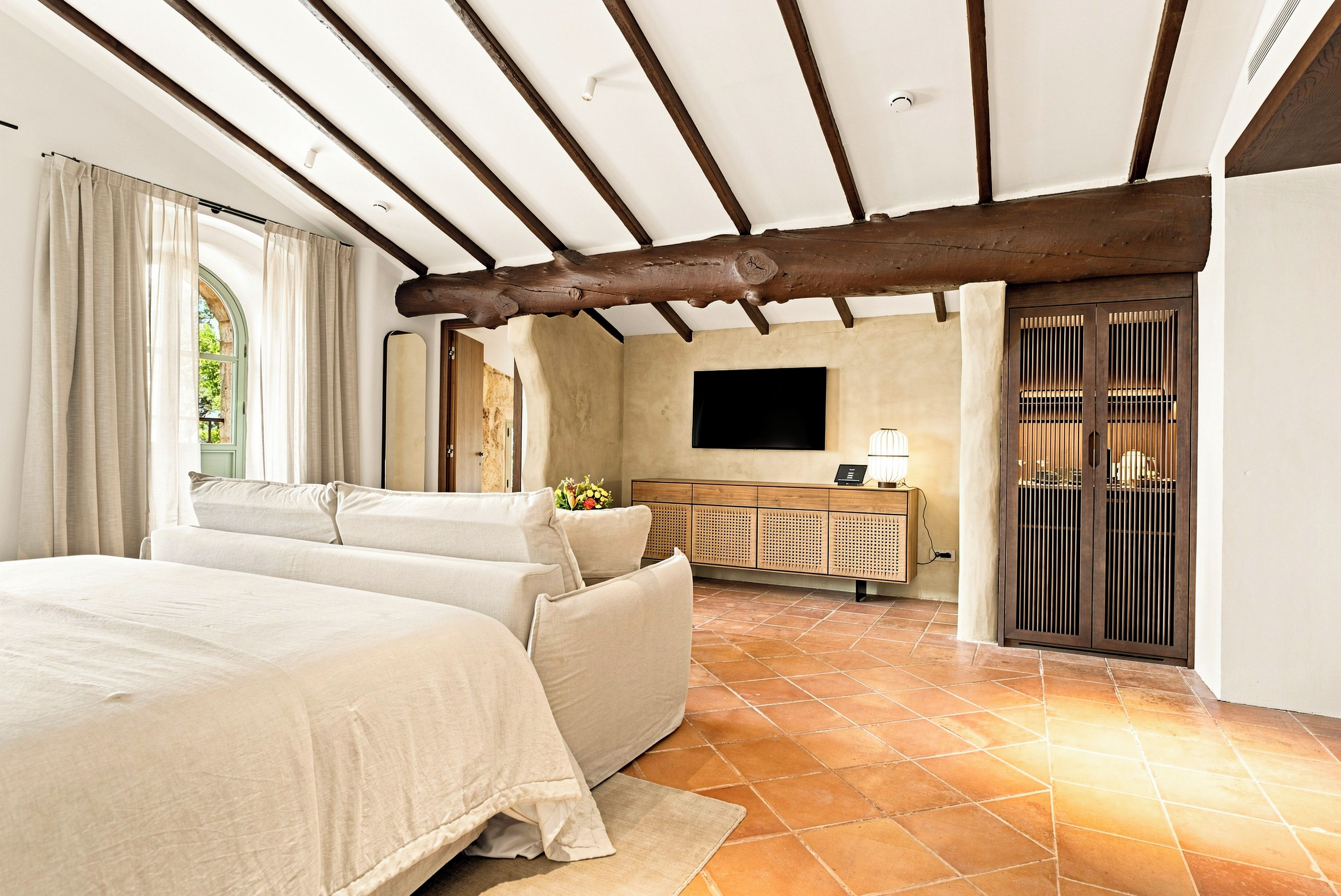 Habitación de hotel con una cama grande, televisión, escritorio y balcón con vistas.