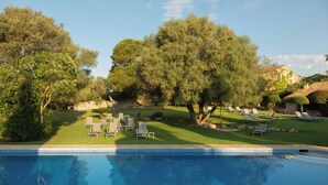Uma área de piscina com espreguiçadeiras e um edifício de pedra ao fundo.