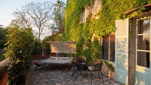 A stone patio with a bed, chairs, and a table. - Rotana la Reserva (Manacor)