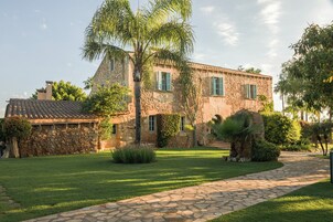 Un edificio de piedra con techo de tejas, un sendero de piedra y un césped bien cuidado.