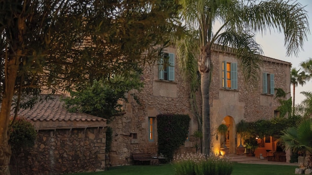 A stone building with a tiled roof, a bench, and a well-maintained garden. - Rotana la Reserva (Manacor)