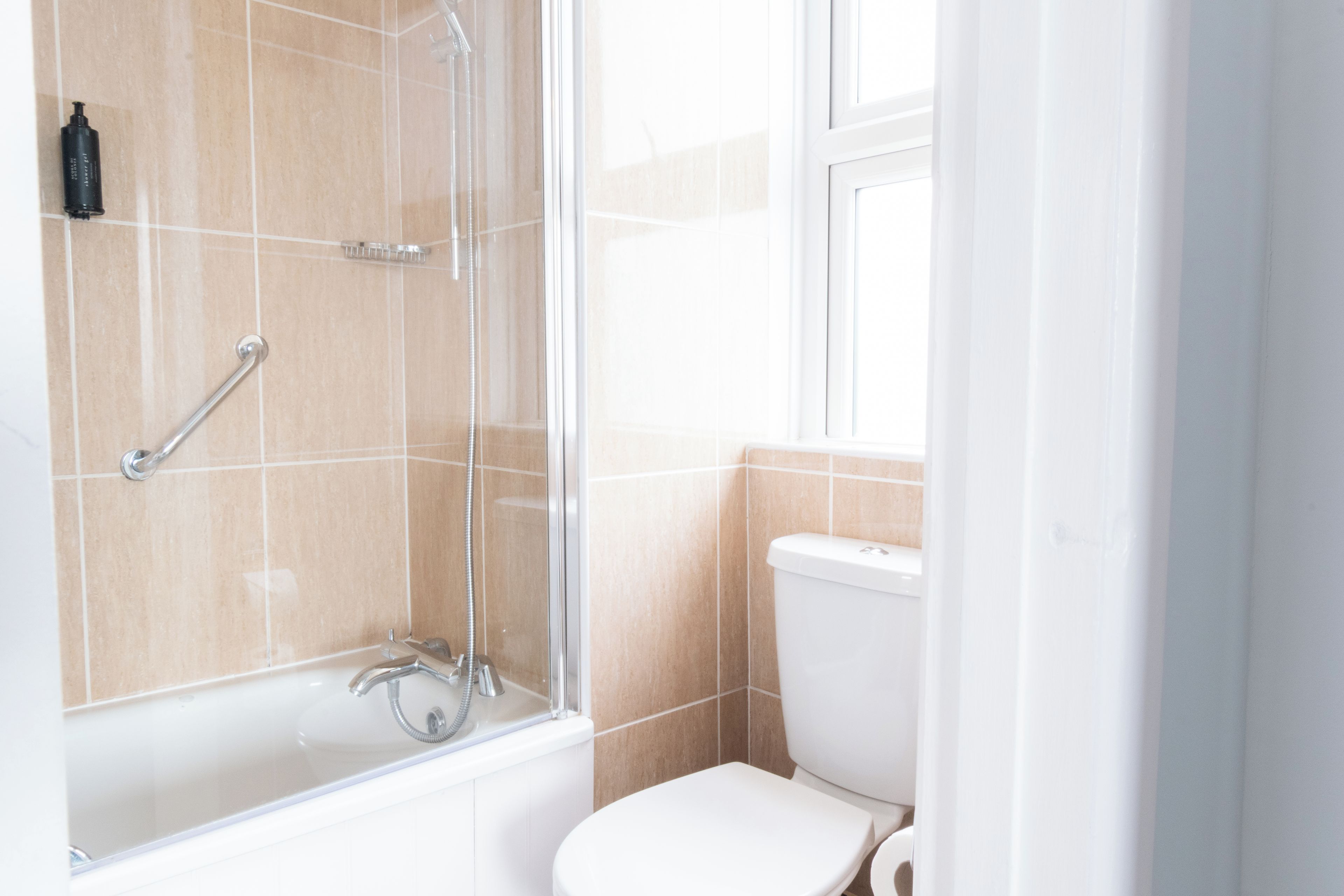 Une salle de bain avec une douche, des toilettes et une fenêtre.