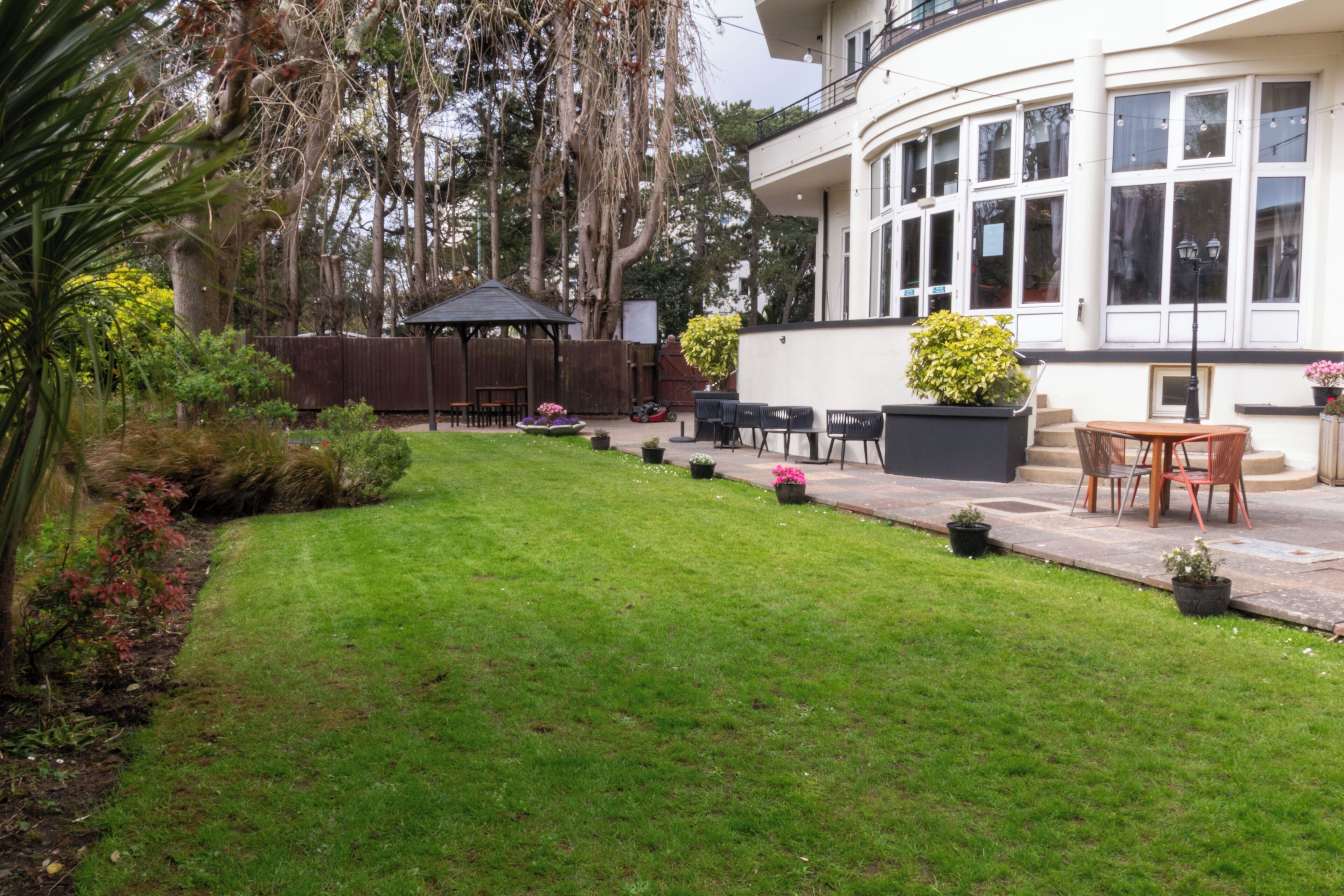 Un jardín bien cuidado con un patio, una valla de madera y un mirador.