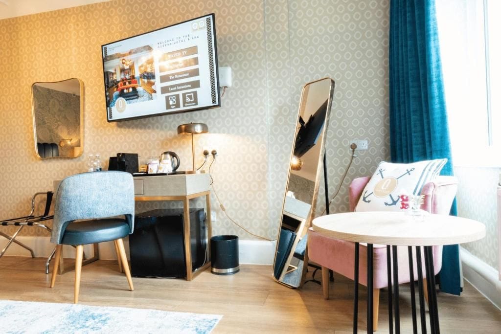 Habitación de hotel con escritorio, silla, mesa redonda y un espejo grande.