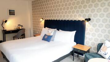 A hotel room with a large bed, a desk, a chair, and a small table.