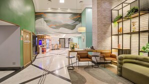 A lobby with a reception desk, seating area, and a brick wall with shelves. - Comfort Hotel Ibirapuera (São Paulo)