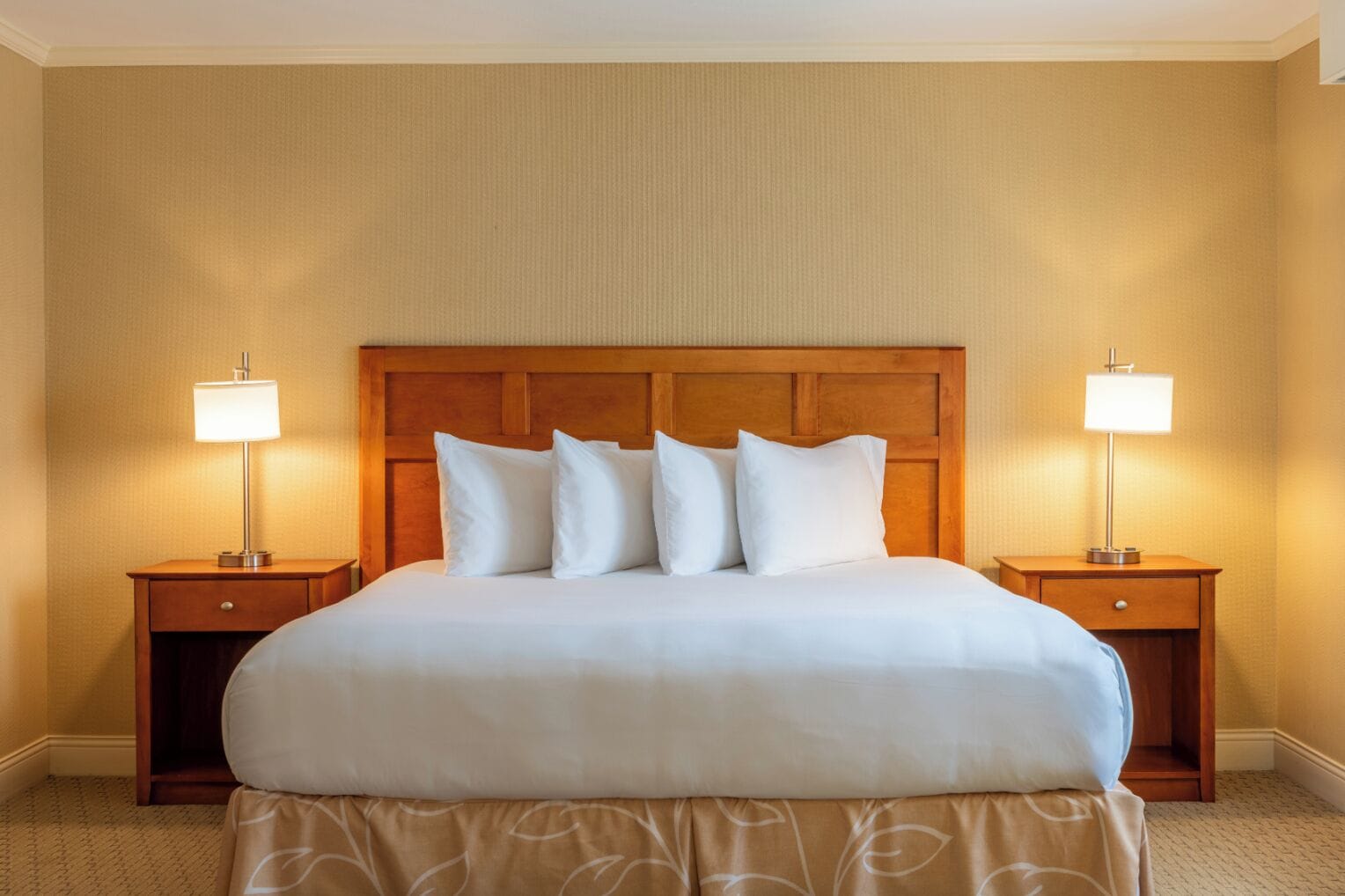 Ein Hotelzimmer mit einem großen Bett, zwei Nachttischen und jeweils einer Nachttischlampe.