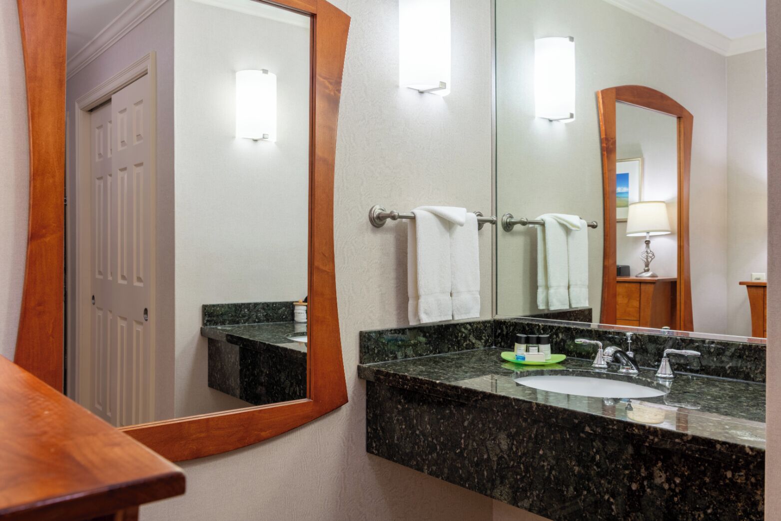 A bathroom with a marble sink, two towel racks, and a large mirror.