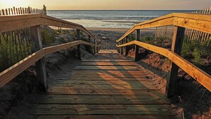 A wooden boardwalk leading to a beach with a wooden fence on either side.