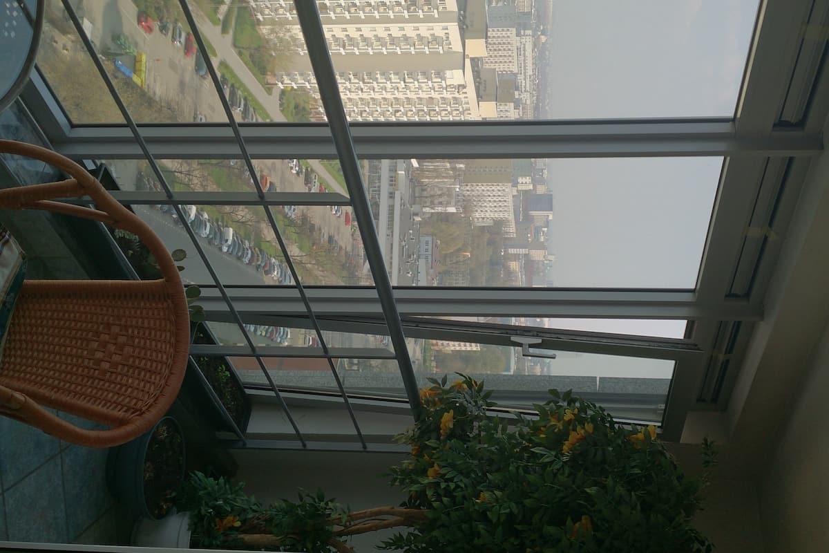 A view from a high-rise window overlooking a cityscape with a parking lot and buildings.