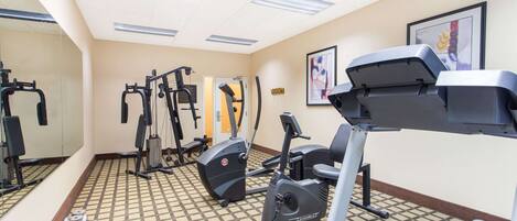 A gym with exercise equipment, a mirror, and a patterned floor.