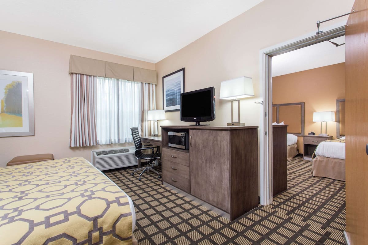 Ein Hotelzimmer mit Bett, Schreibtisch, Fernseher und einem durchgehenden Türspalte sichtbaren Badezimmer.