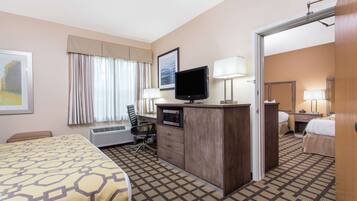 A hotel room with a bed, desk, television, and a bathroom visible through an open door.