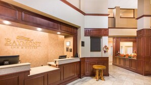 Un espace d’accueil avec une enseigne Baymont Inn & Suites, un comptoir de réception, une petite table ronde et une couronne décorative.