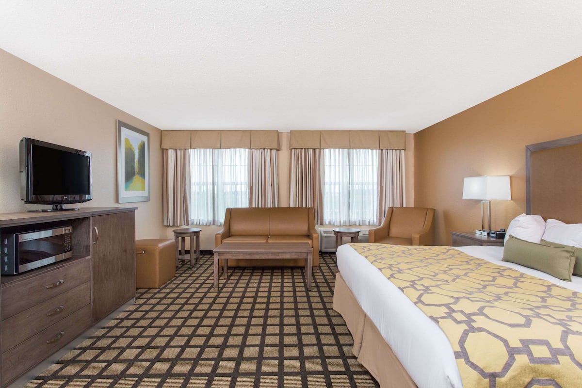 Ein Hotelzimmer mit Bett, Fernseher, Sofa, Schreibtisch und Stuhl.