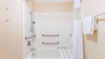 A bathroom with a bathtub, grab bars, a shower curtain, and a towel rack.