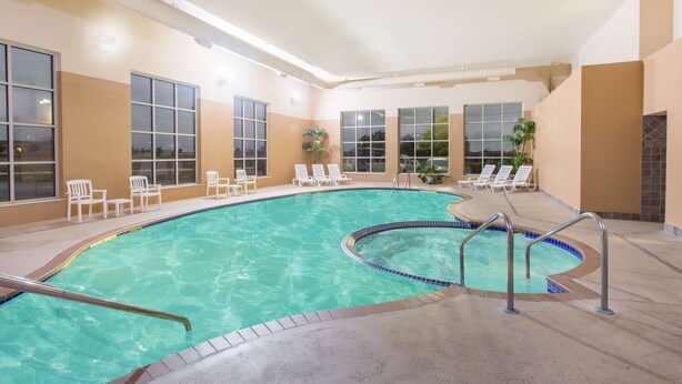 Une piscine intérieure à l’eau claire, entourée de chaises longues et bordée d’une terrasse carrelée.