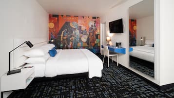 Habitación de hotel con cama, escritorio, silla y un espejo grande.