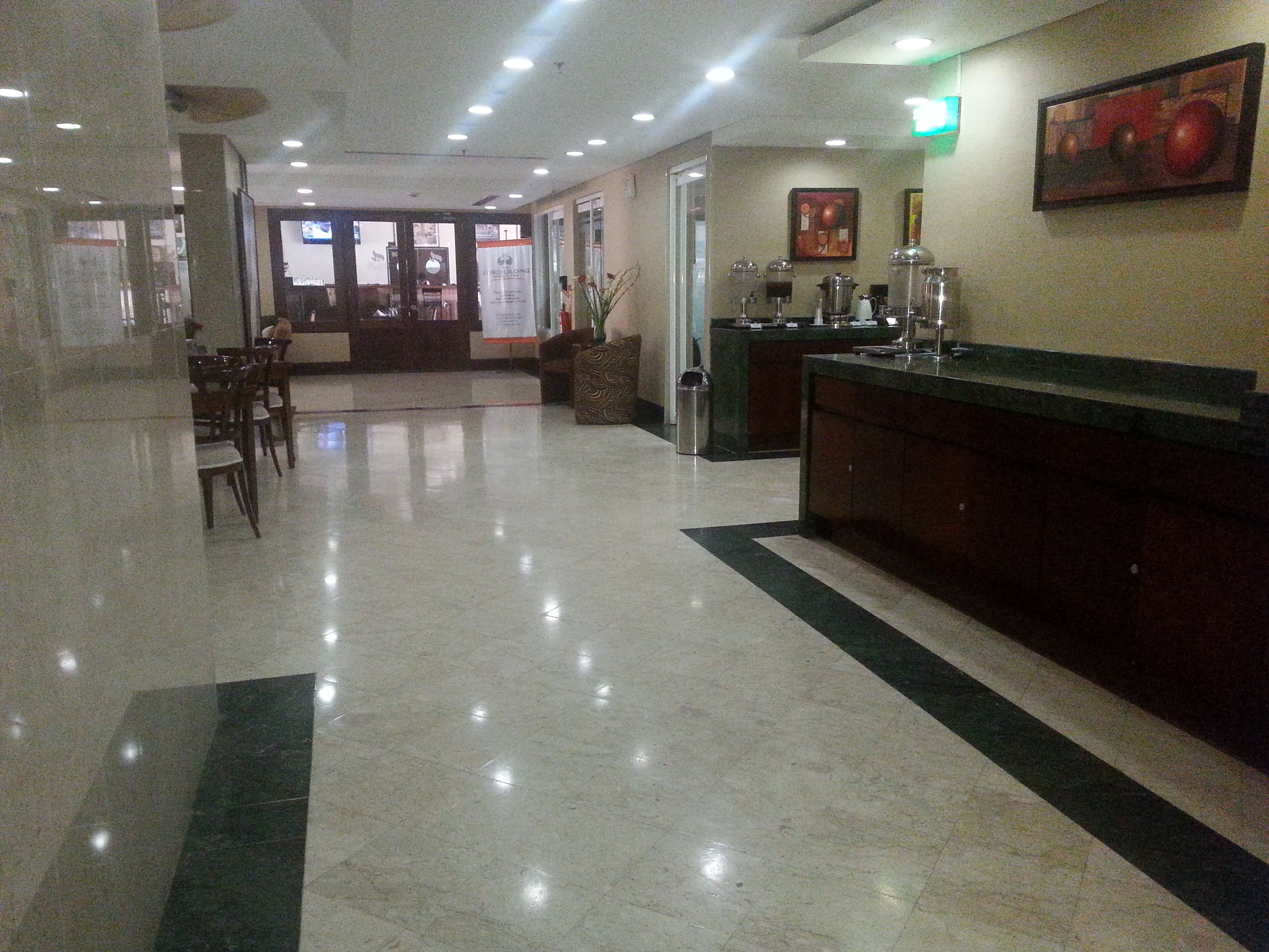 A hotel lobby with a reception desk, seating area, and a coffee station.