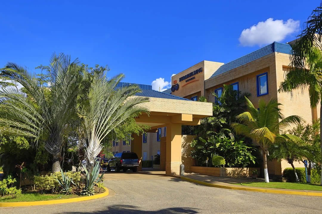 Un hotel con un ingresso imponente, palme e cielo azzurro.
