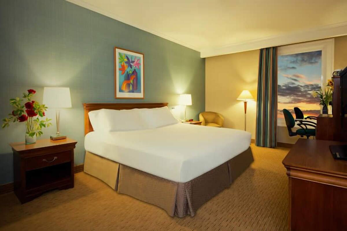 Ein Hotelzimmer mit einem großen Bett, Nachttischlampen, einem Schreibtisch und einem Stuhl.