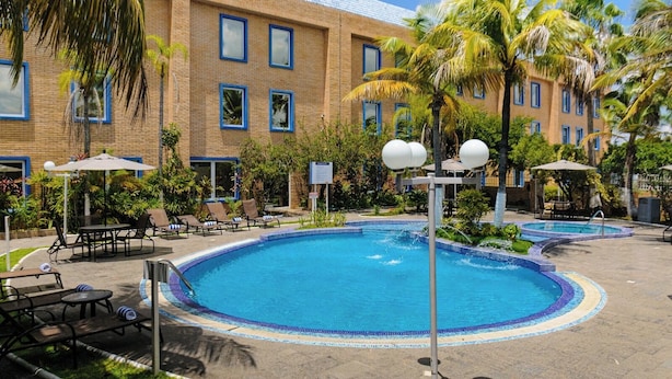 Un hôtel doté d’une piscine, de chaises longues et de palmiers.