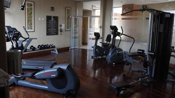 Un gimnasio con cintas de correr, elípticas y equipo de levantamiento de pesas.