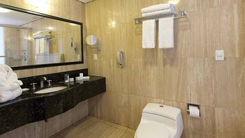 A modern bathroom with two sinks, a toilet, a large mirror, and a towel rack.