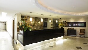 A modern reception area with a black reception desk, potted plants, and a stone accent wall. - Eurobuilding Express Maracay (Maracay)