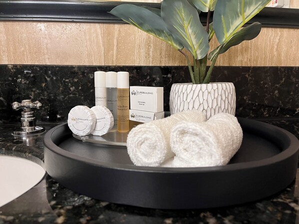 Un meuble-lavabo de salle de bain avec des articles de toilette, un bonnet de douche et une plante.