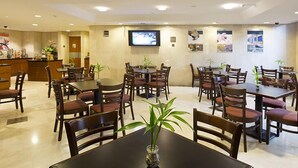 A hotel dining area with multiple tables and chairs, a reception desk, and a television mounted on the wall. - Eurobuilding Express Maracay (Maracay)