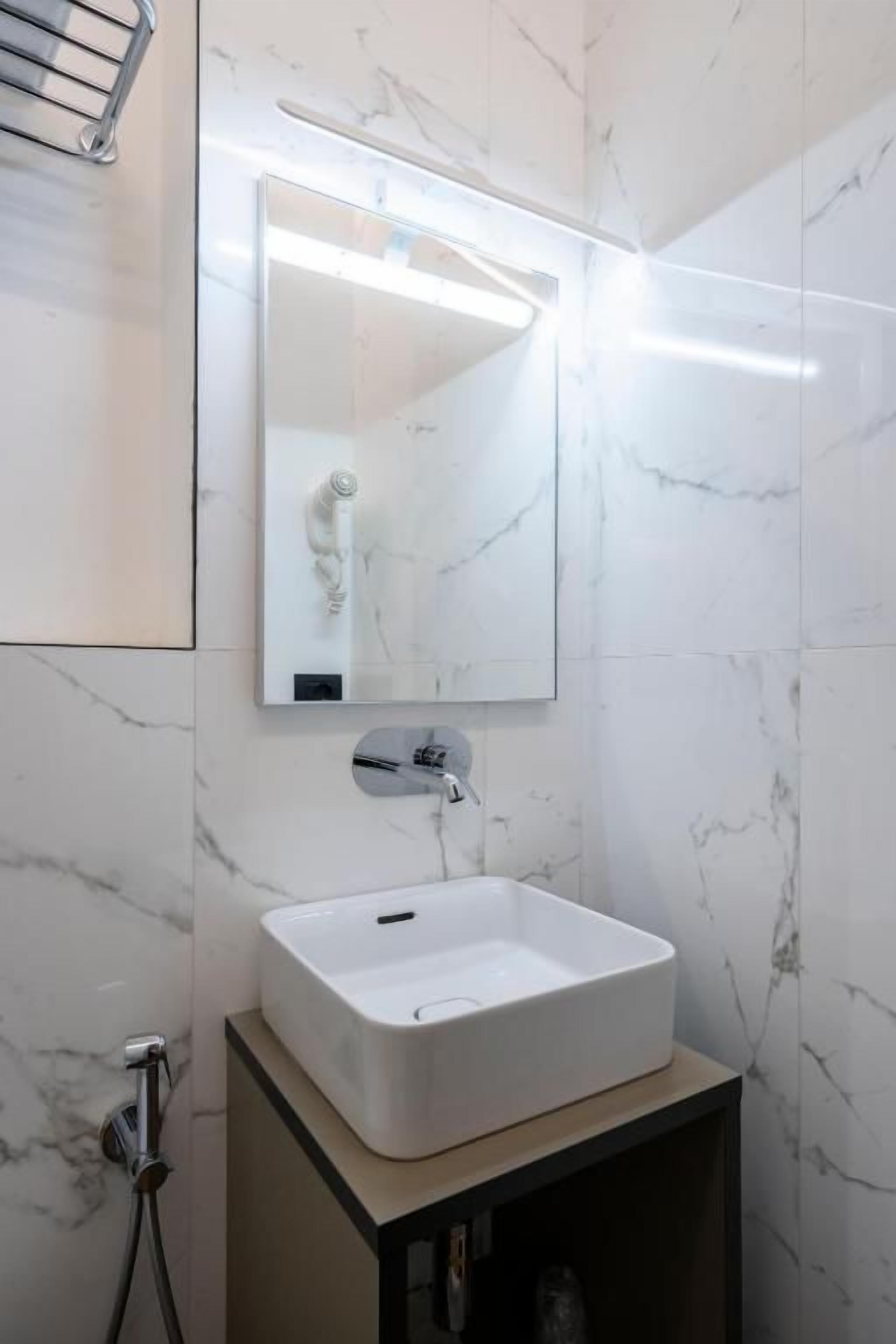 A bathroom with a white sink, a mirror, and a shower.